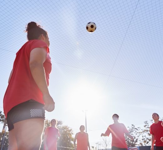 Womens Football Team Kicking Ball Whilst Training For Soccer Match On Outdoor Astro Turf Pitch